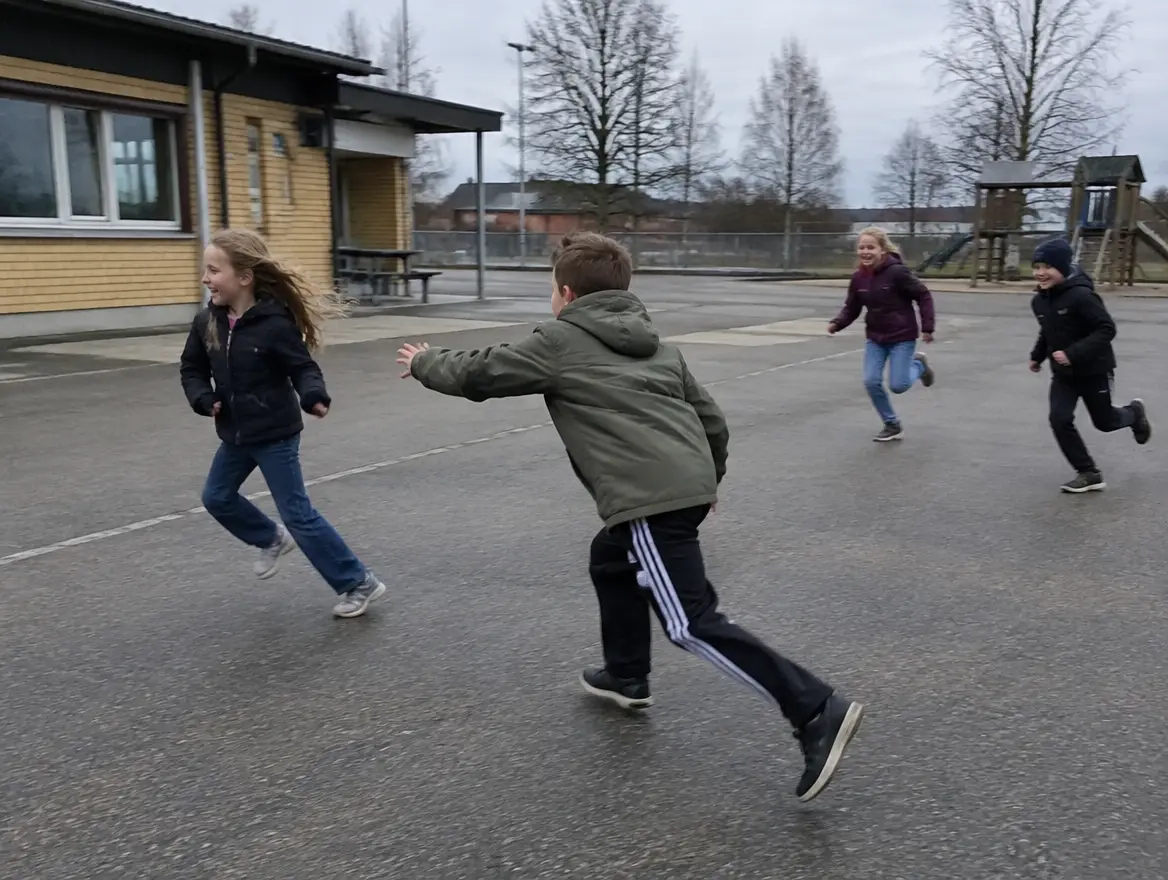 Barn springer över skolgården och leker en jaktlek